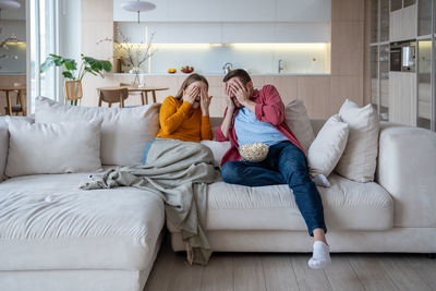 Portrait of smiling couple sitting on bed at home