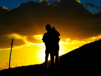 Silhouette man photographing against sky during sunset