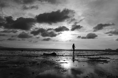 Silhouette woman wading in sea against sky