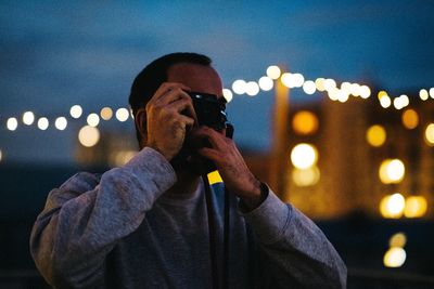 Midsection of man photographing illuminated smart phone at night