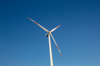 Low angle view of windmill against blue sky