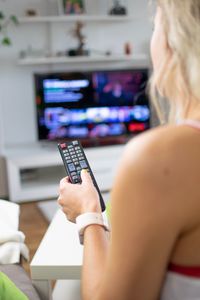 Midsection of woman watching tv at home