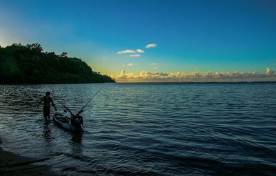 Silhouette man standing in sea during sunset