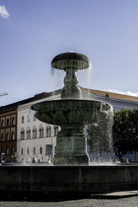 Fountain in front of built structure against clear sky