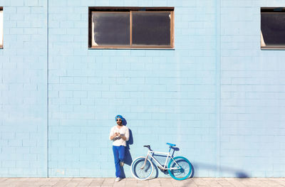 Full length of woman on bicycle against building