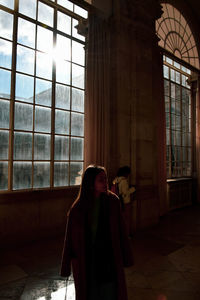 Woman standing in building by window