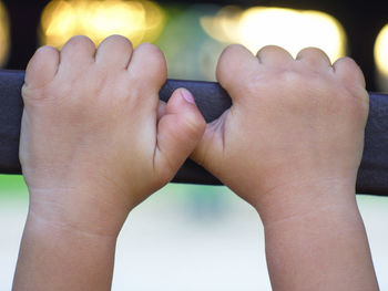 Cropped hands of child holding railing