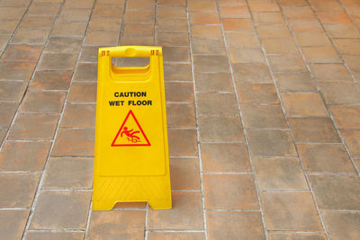 High angle view of yellow sign on footpath