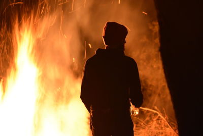 Rear view of silhouette man against fire at night