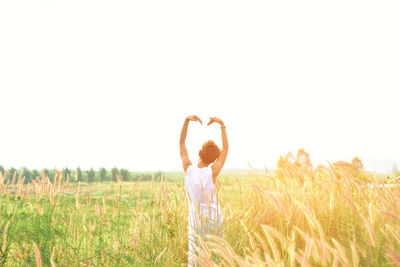 Girl standing in wheat field against clear sky