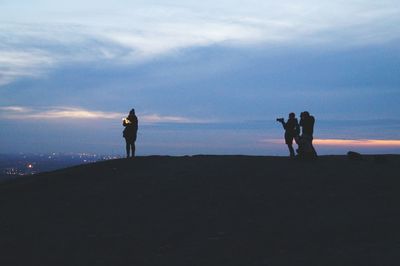 Silhouette people photographing on landscape against sky