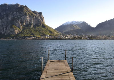 Pier over lake by mountains against sky