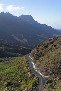 Scenic view of road by mountains against sky