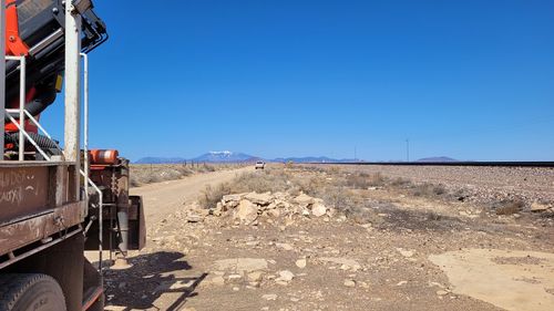 Road leading towards mountain against clear blue sky