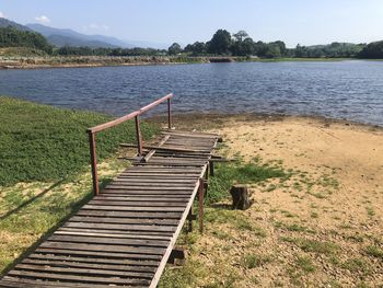 Empty boardwalk by lake against sky