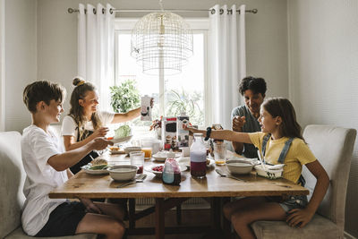 Parents having breakfast with children over table at home