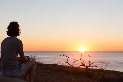 Man looking at sea against sky during sunset