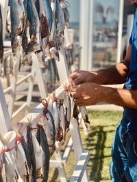 Midsection of man hanging fish outdoors