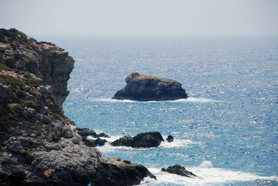 Rocks in sea against clear sky