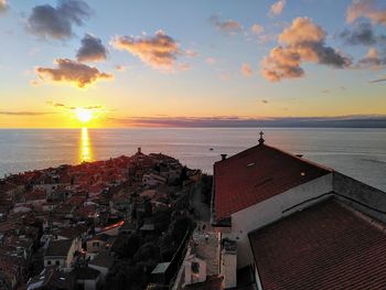 High angle view of townscape by sea against sky during sunset