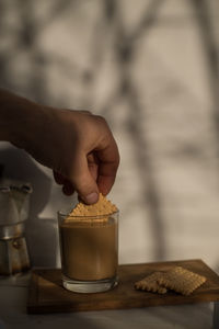 Midsection of person holding drink in glass on table