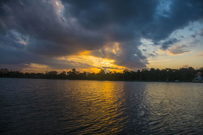 Scenic view of lake against dramatic sky during sunset