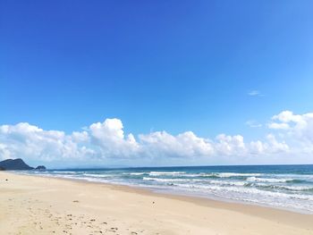 Scenic view of beach against blue sky