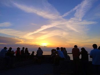 Silhouette people standing on beach against sky during sunset