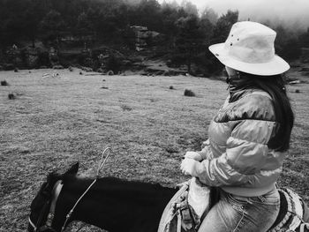 Side view of woman riding horse on field