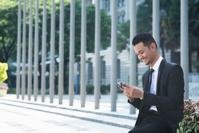 Businessman using phone outdoors