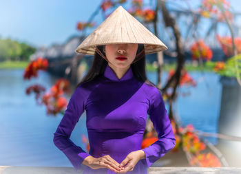 Woman wearing hat standing against plants