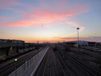 Railroad tracks in city against sky during sunset