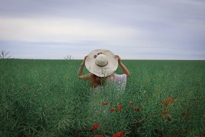 Rear view of woman standing on field against sky