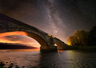 Arch bridge over water at night