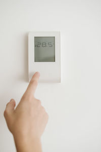 Finger touching thermostat on the wall