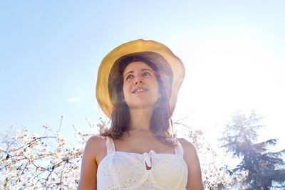 Low angle view of young woman wearing hat against sky