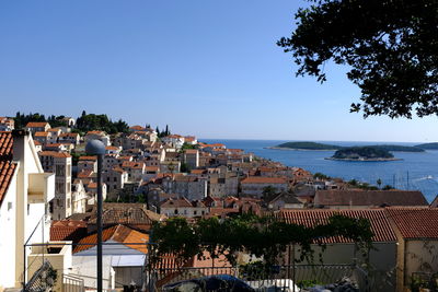 Townscape by sea against clear blue sky