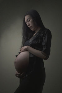 Beautiful young woman standing against gray background