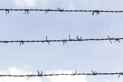 Low angle view of barbed wire against sky