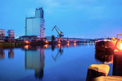 Reflection of illuminated pier on river against sky