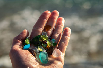 Cropped hand of person holding multi colored stones