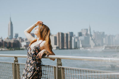Woman standing by railing against river