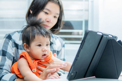 Portrait of mother and woman using mobile phone