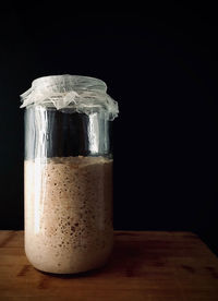 Close-up of glass jar on table against black background