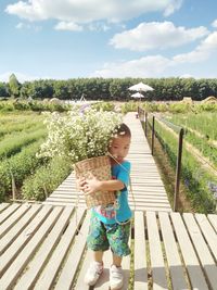 Girl standing by plants against sky