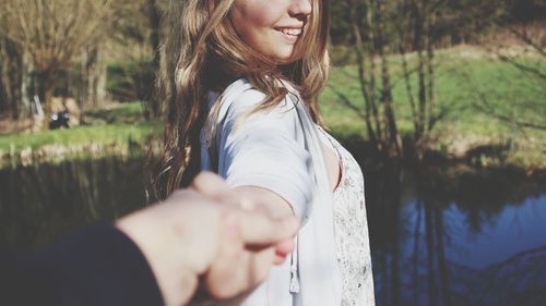 Close-up of woman with hand on tree