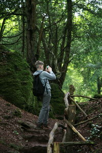 Woman standing on tree trunk in forest