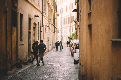 People walking on alley amidst buildings in city