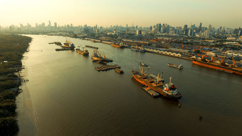 High angle view of boats in river by buildings during sunset