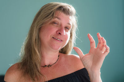 Portrait of a woman looking into the camera against a light green background. 